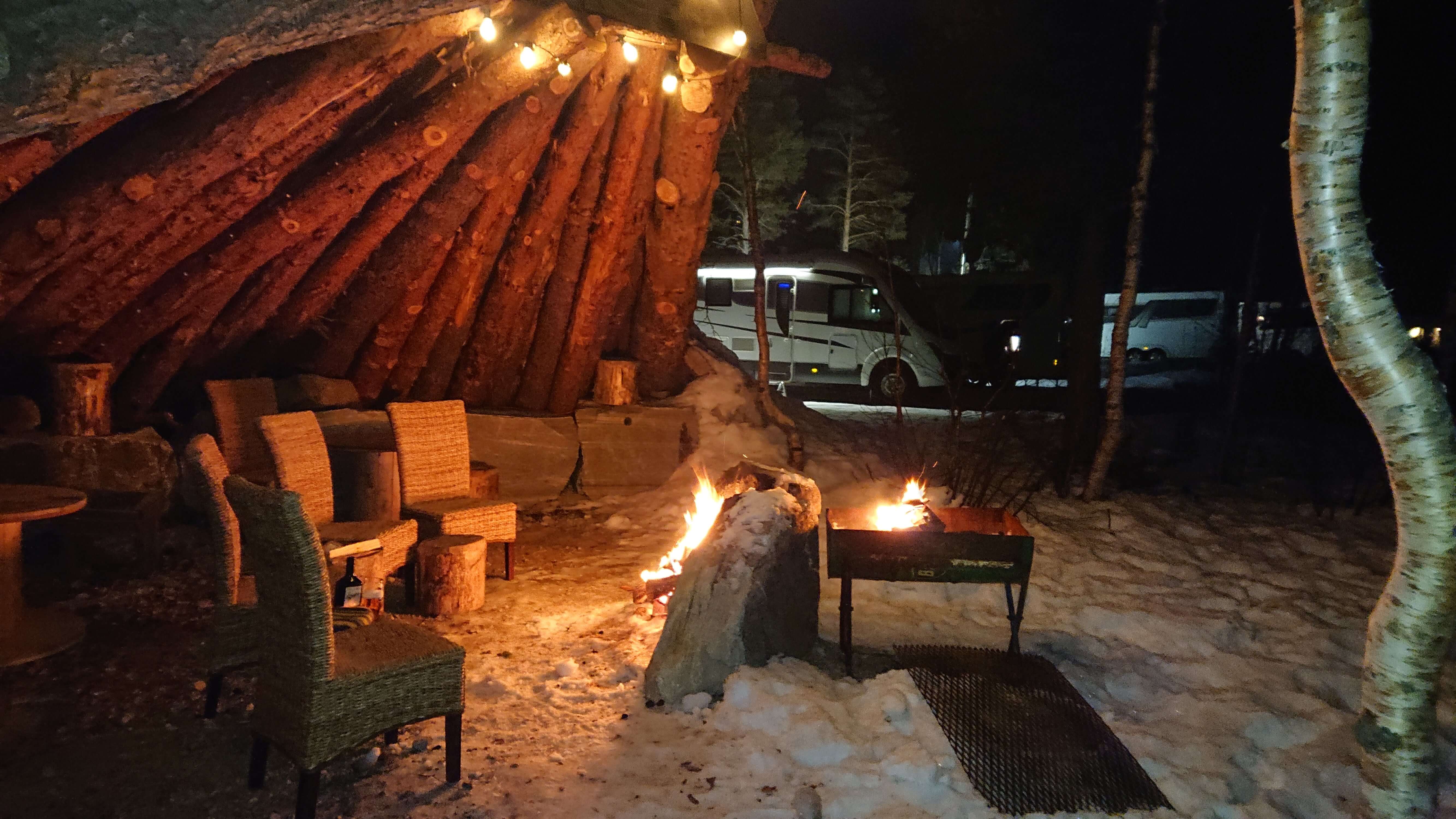 I bildet er det bål i en gapahuk og tomme stoler. Snø og lyslenke ser vi også.